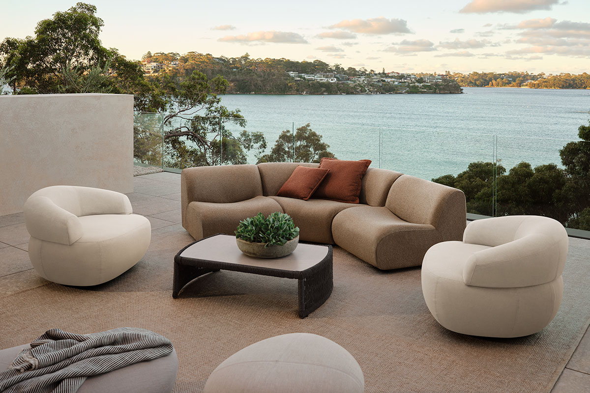 1977 Outdoor Sofa and armchairs upholstered in Zenith Biscotti and Sable, arranged on a terrace overlooking the water.