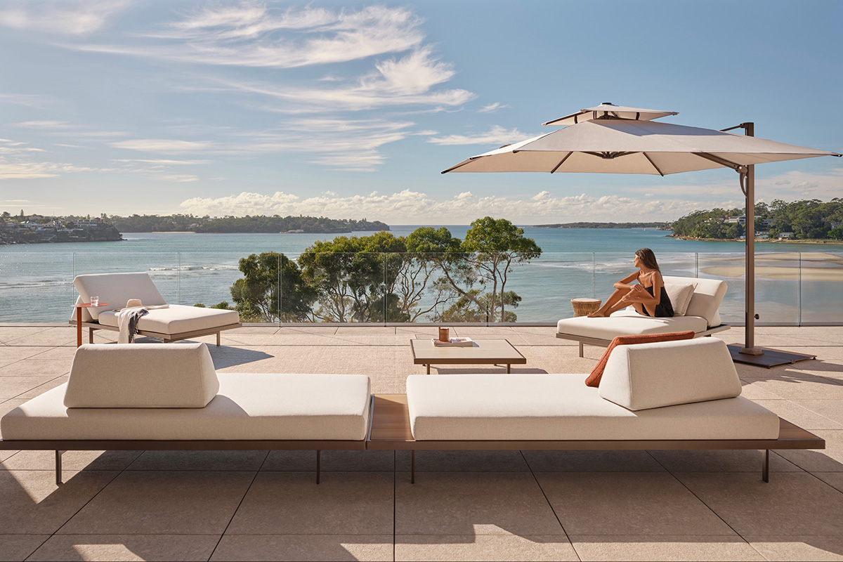 Plateau Outdoor Sofas in a setting overlooking Sydney Harbour, featuring modular seating, sun loungers and umbrellas on a sunlit terrace.
