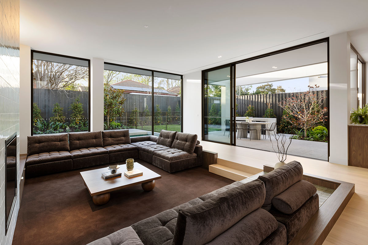 Modern sunken lounge setting styled with a modular sofa and large rug in a rich chocolate brown.