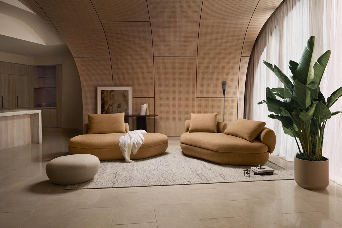 Sustainable materials and natural textures blend in an organic modern style living space defined by plants and island sofas.