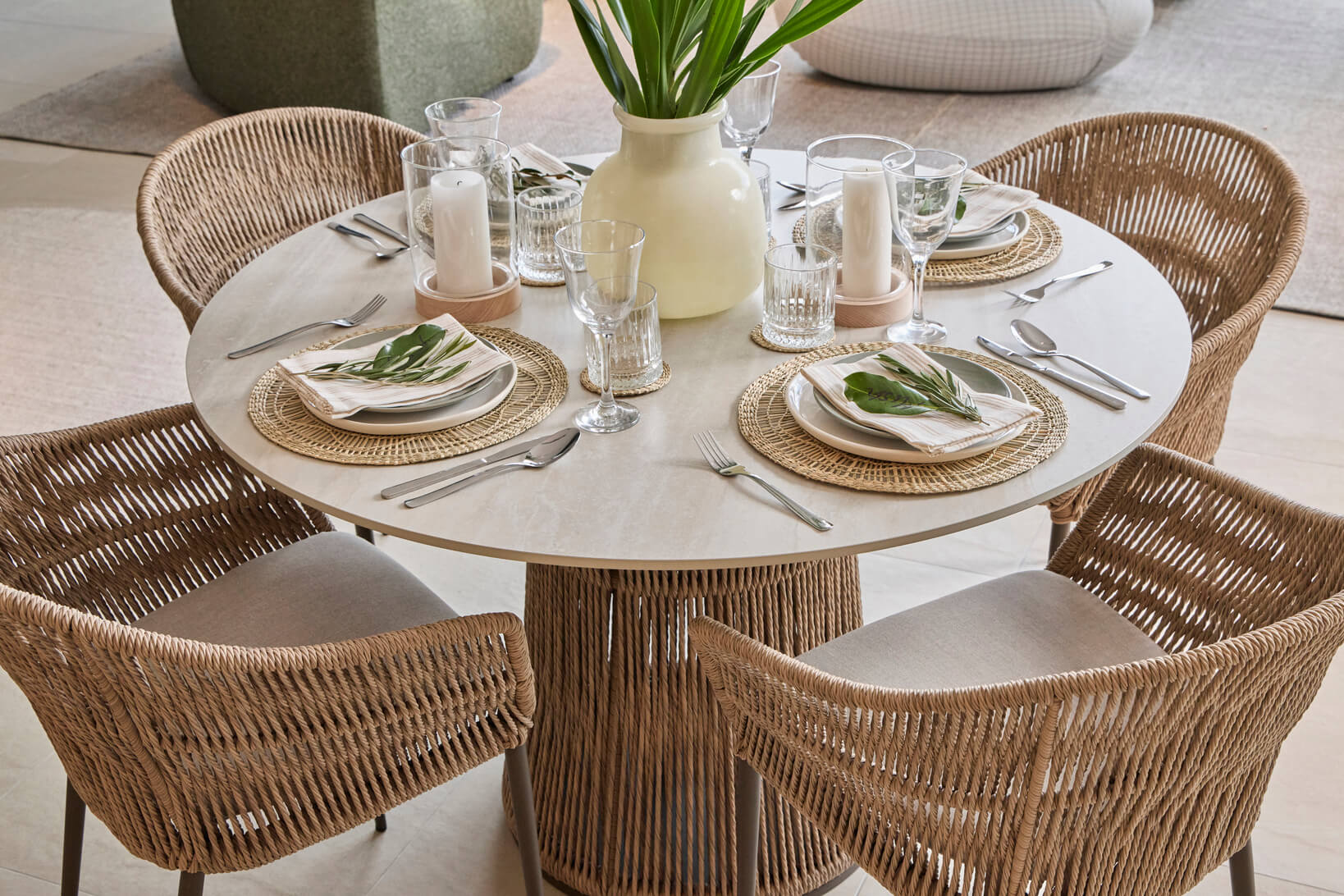 Woven dining chairs and outdoor table styled in an earthy setting with rattan placemats, linen napkins and eucalyptus leaves.
