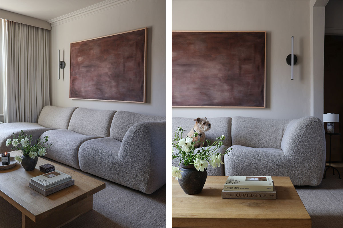 Soft neutral curved modular sofa styling in a calm neutral room with a large deep-red artwork and fresh flowers.
