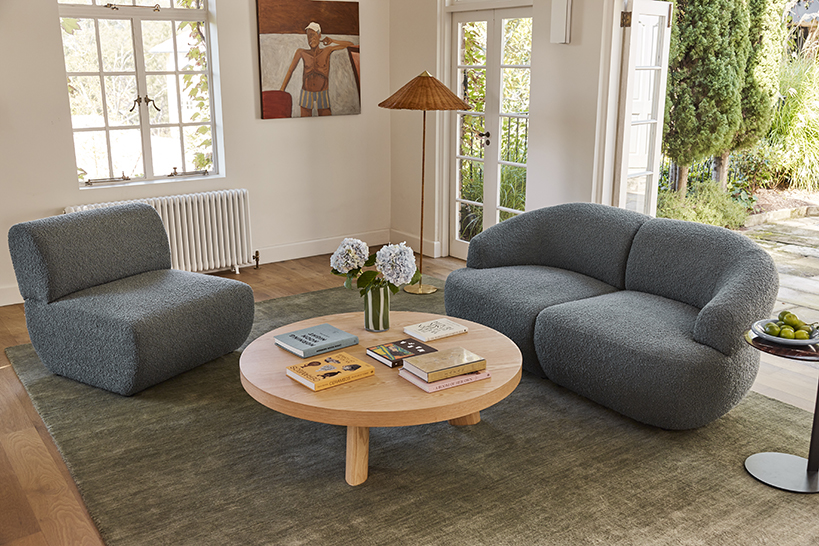 A camel-toned modular sofa complemented by a tonal accent chair, rug and coffee table in a light-filled contemporary living space.